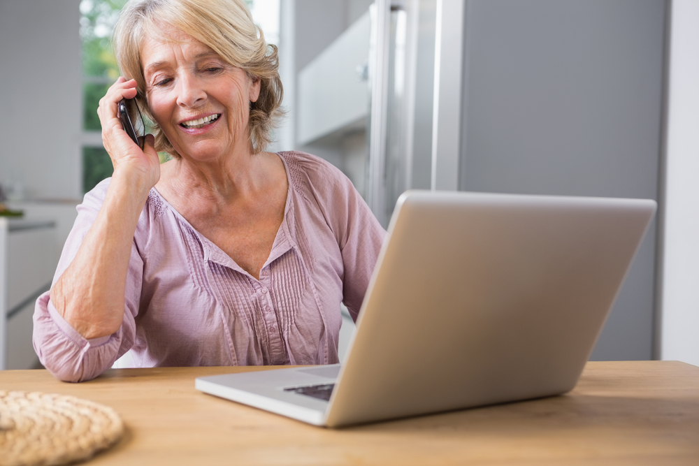 Happy mature woman using her laptop and calling